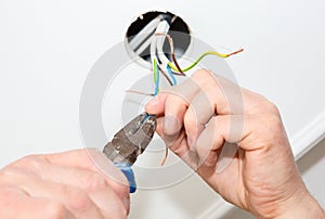 Man is holding pliers in his hands. Electrical insulator for light bulb. Adhesive tape for maintenance repair works in the flat.