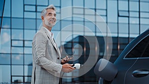 Man holding power supply cable at electric vehicle charging station, closeup