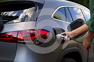 Man holding power supply cable at electric vehicle charging station, closeup