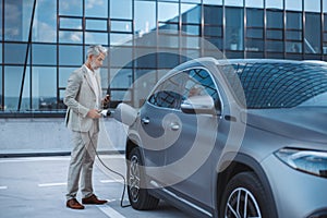 Man holding power supply cable at electric vehicle charging station, closeup