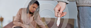 man holding pregnancy test, upset african