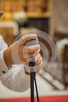 Man holding and preparing microphone to use in musical performance. Rustic interior environment, example temple or church