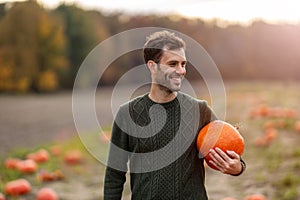 Man holding pumpkin in pumpkin patch field photo