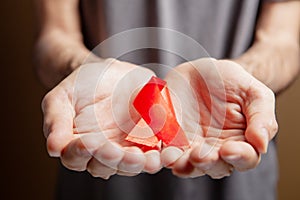 a man holding a red aids ribbon