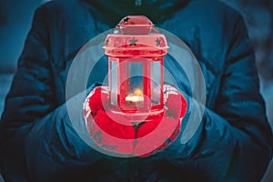 Man holding a red candle lantern with a candle close up