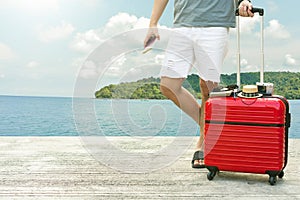 Man holding Red luggage with passport on blurred city background for activity lifestyle outdoors freedom or travel tourism