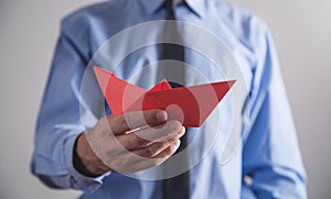 Man holding red origami paper boat