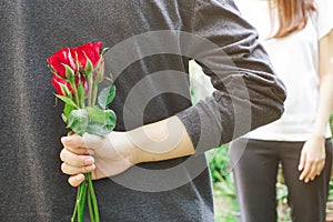 Man holding red roses behind his back.Valentineâ€™s day gift concept