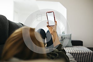 Man holding a red smartphone on a sofa in a livingroom