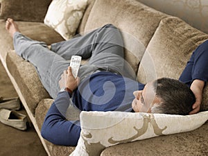 Man Holding Remote Control While Lying On Sofa