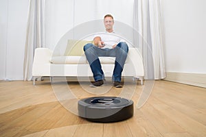 Man holding remote control of robotic vacuum cleaner