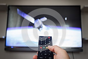 Man holding remote control and watching satellite scene