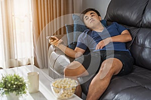 Man holding remote control and watching TV while sitting on sofa