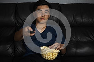 Man holding remote control and watching TV while sitting on sofa