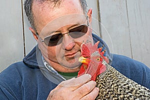 Man holding a rooster in his arms
