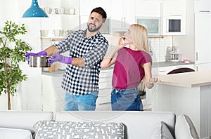 Man holding saucepan under water leakage from ceiling while woman calling plumber