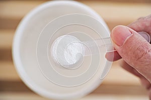 Man holding a scoop with D-ribose powder inside photo