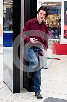 Man holding a shopping bags and using a mobile phone