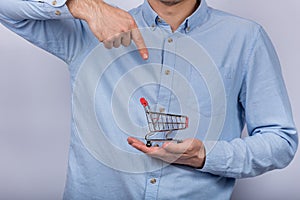 Man holding shopping cart and pointing with finger. Convenient shopping concept