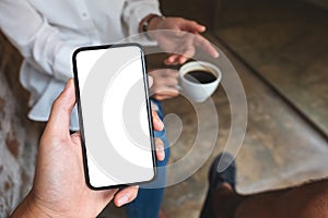 a man holding and showing mobile phone with blank desktop screen to his friend while having conversation together