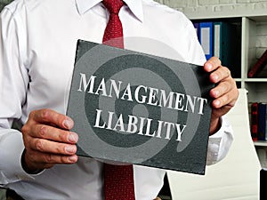 A man holding a sign with the inscription management liability.