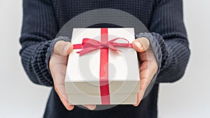 Man holding a silver gift box on a gray background