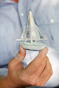 Man holding a small toy sailing boat - concept for sailing or cr