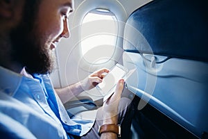 Muž držanie chytrý telefón prázdny obrazovka v lietadlo 