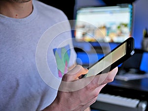 Man holding smartphone / cell phone in hand with blank screen.