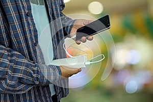 Man is holding smartphone is charging with backup battery or Power bank on bokeh background