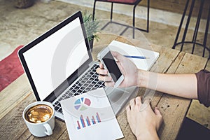 Man holding smartphone and chart laptop coffee on table