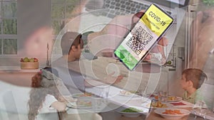 Man holding a smartphone with qr code on screen against caucasian family having lunch together