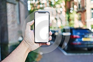 Man holding smartphone showing white blank screen at car parking