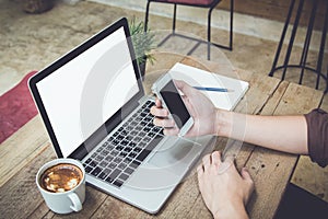 Man holding smartphone on table with laptop and coffee