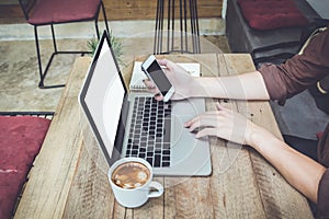 Man holding smartphone on table with laptop and coffee