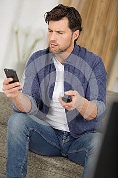 man holding smartphone and using app with remote control