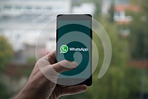 Man holding smartphone with Whatsapp with the finger on the screen