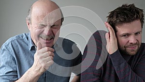 Man holding sneezing with closed eyes. His coworker try to hide from microbes.
