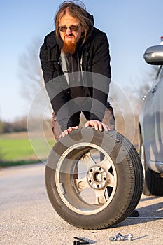 Man holding spare tire at roadside pitstop photo
