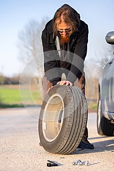 Man holding spare tire at roadside pitstop photo