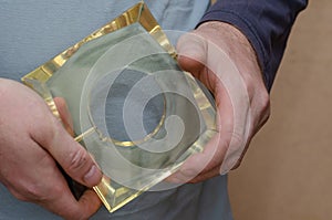 A man is holding a square glass figure in his hand. Transparent