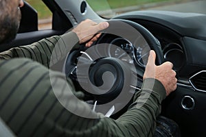 Man holding steering wheel in car, closeup. Driving test