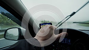 Man holding steering wheel, driving a car in the rain, careful driving in rainy day, left hand drive, close up
