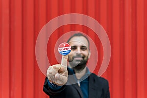 Man holding a sticker with the American flag colors with 'I voted today' written on it