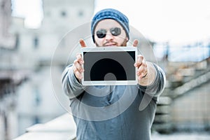 Man holding a tablet with both hands - urban blurred background