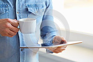 Man holding tablet and cup of coffee