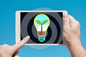 Man holding a tablet device with light bulb eco concept illustration