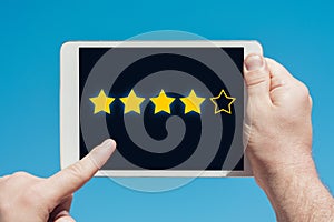 Man holding a tablet device and rating stars as evaluation, rank