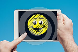 Man holding a tablet device showing happy smiley icon