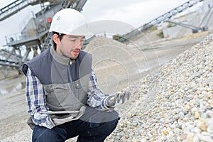 Man holding tablet looking at pile stones in quarry